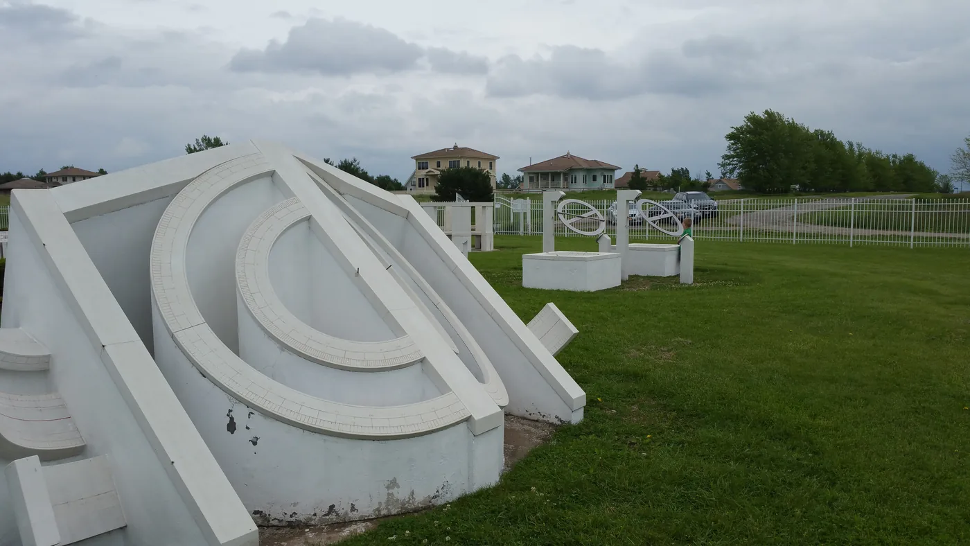 White sculptural sundial instruments of an open-air observatory on a lawn