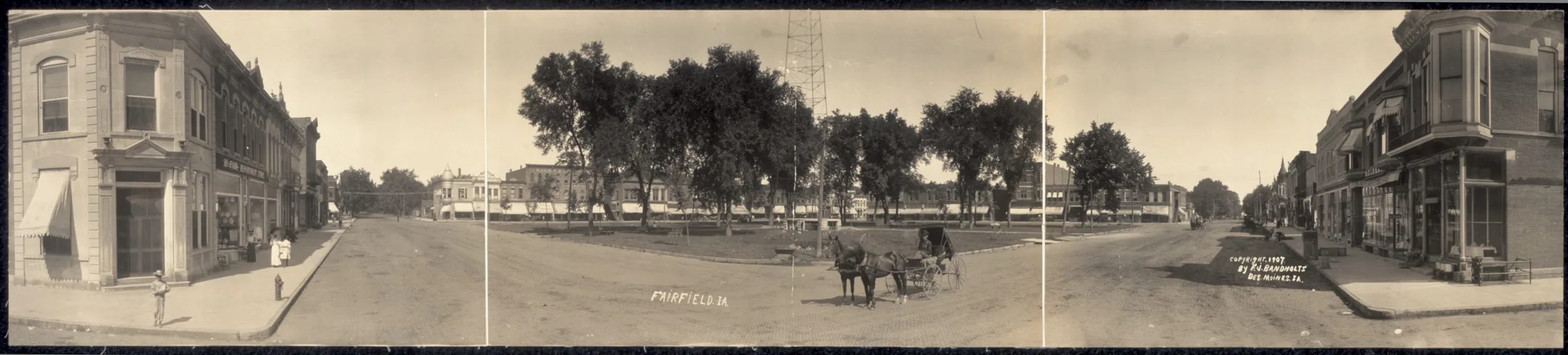 Panoramic photograph of Fairfield's town square in 1907, with storefronts, trees and a horse-drawn carriage